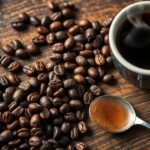 Close-up of coffee beans and a steaming cup.