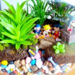 Vibrant terrarium with plants and colorful pebbles.