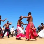 Diverse people practicing Capoeira outdoors in traditional attire.