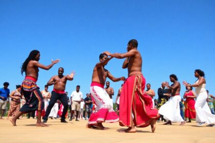 Diverse people practicing Capoeira outdoors in traditional attire.