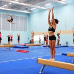 Diverse gymnasts performing skills in a bright gymnasium.